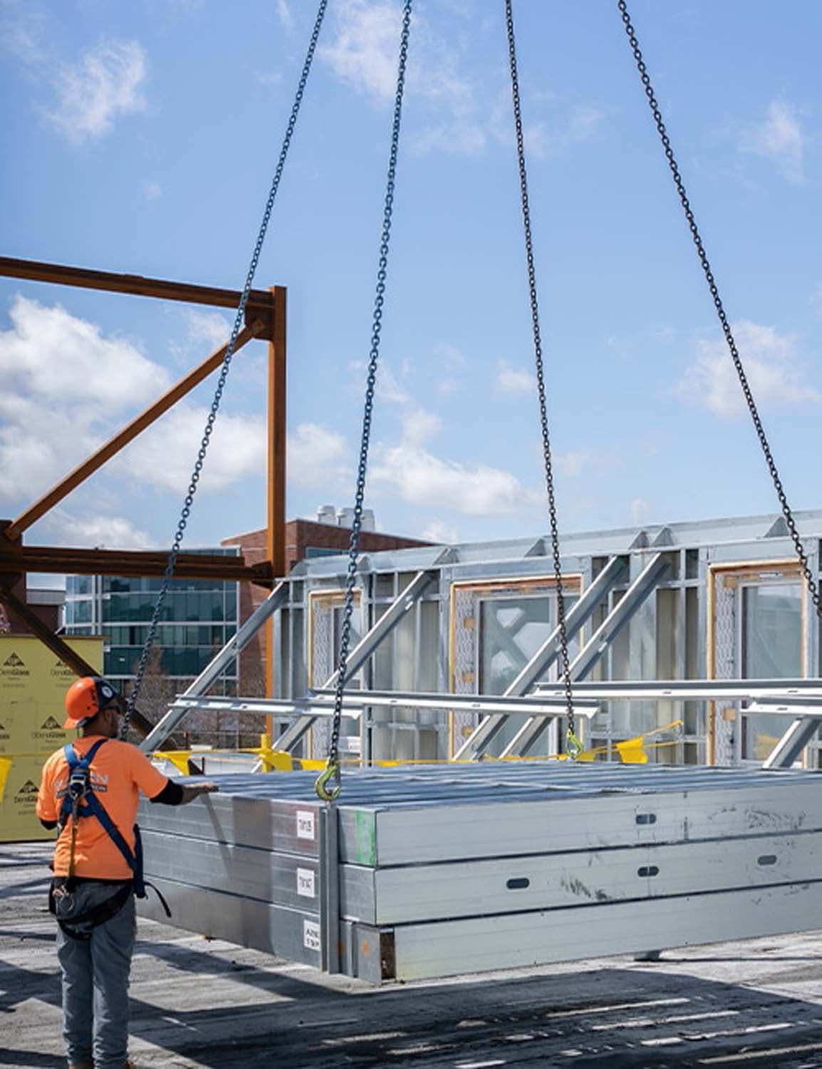 Construction worker guiding PIVOT Systems wall panels being lifted by crane