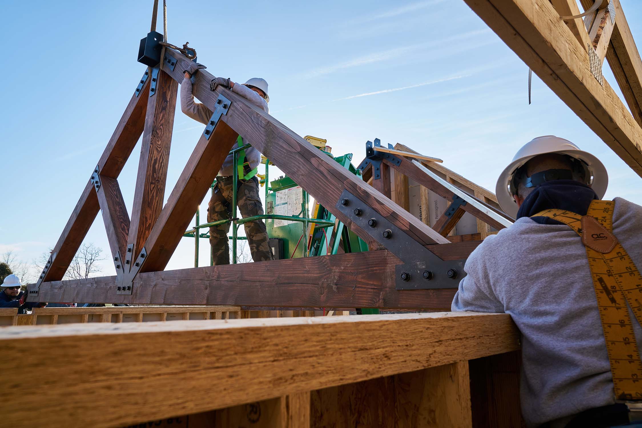 Workers installing an engineered timber truss on a building