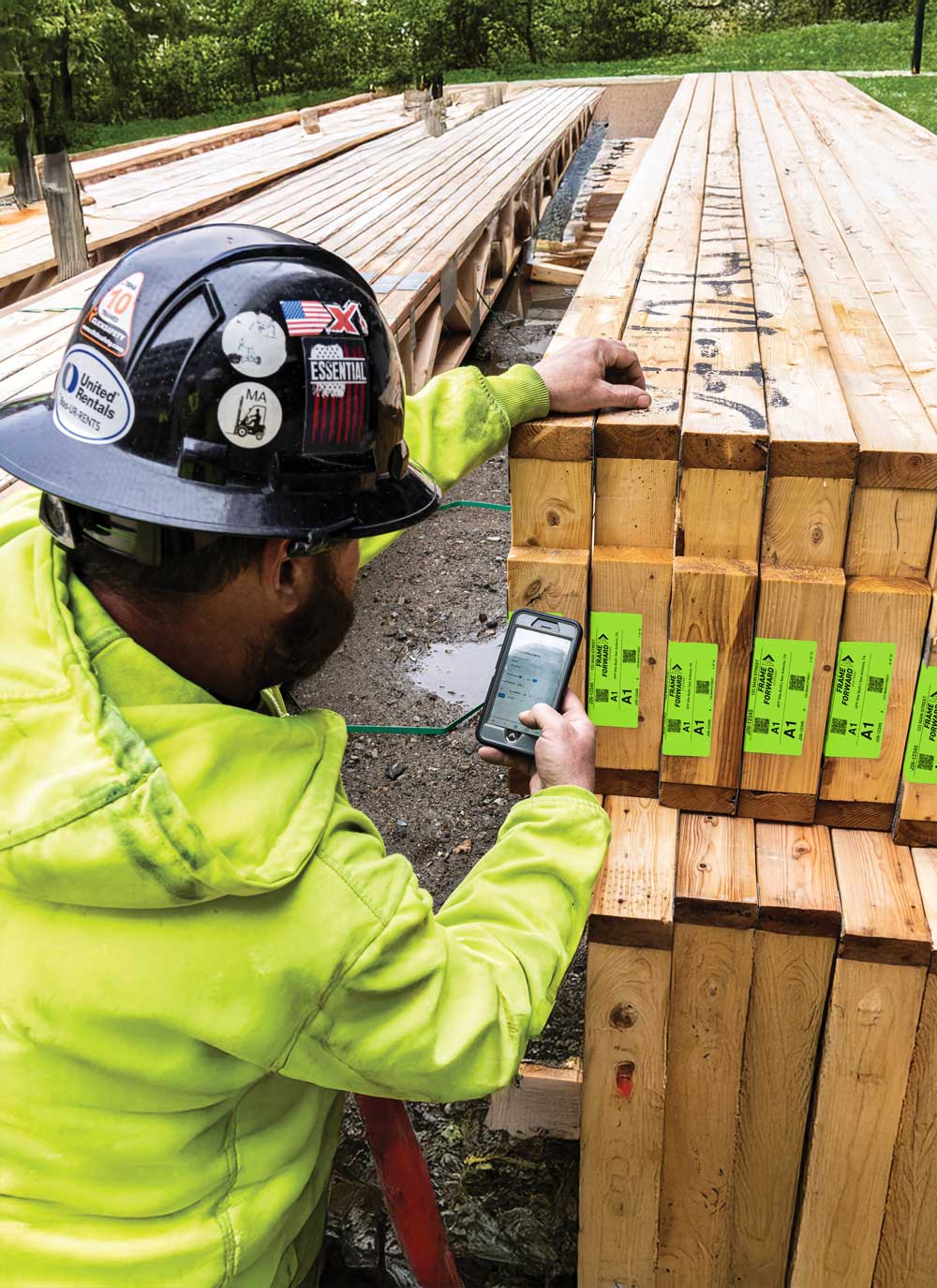 Worker scanning TRUSSTRAX QR code label on lumber at job site