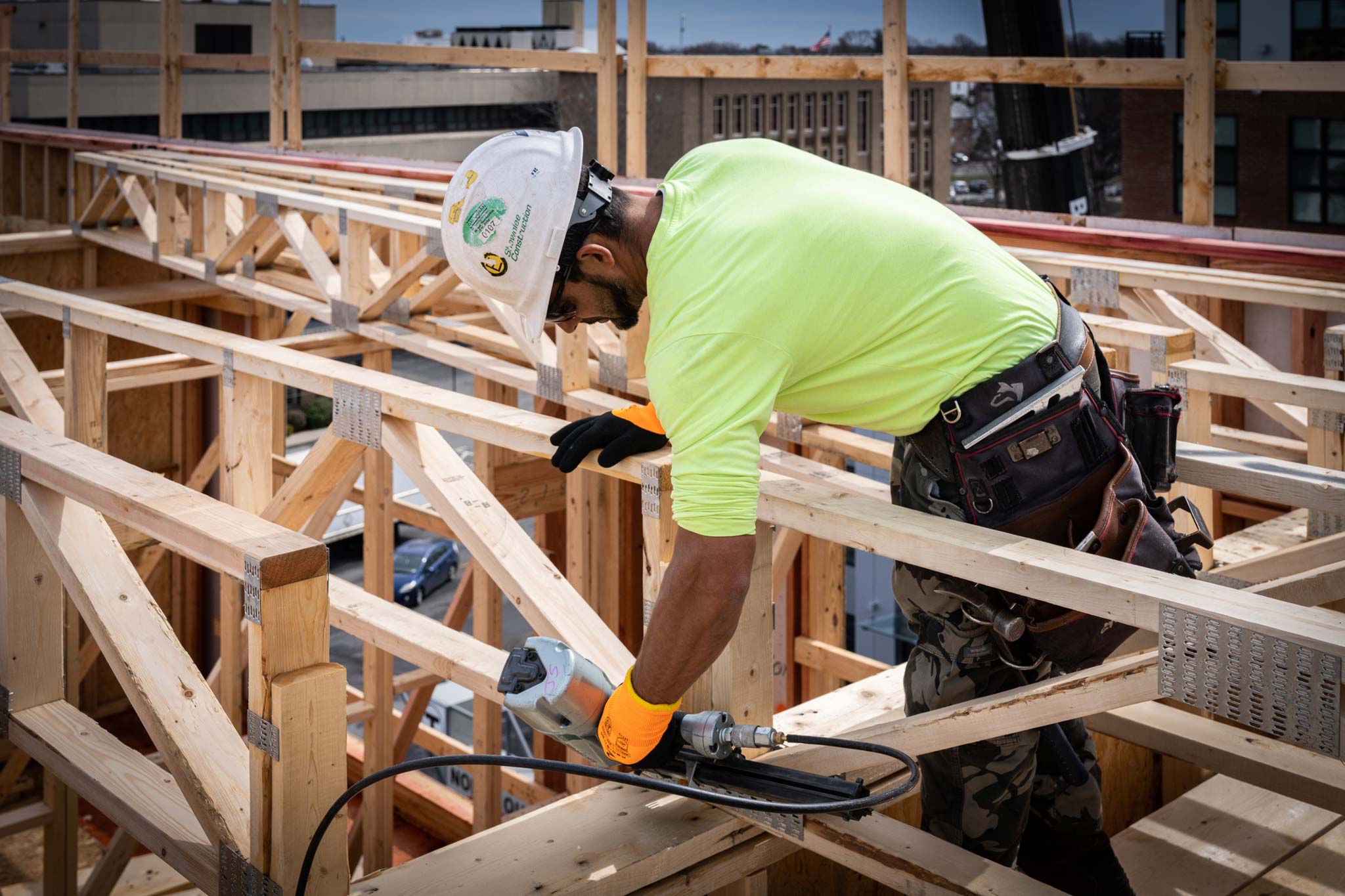 Construction worker installing roof trusses on a building frame